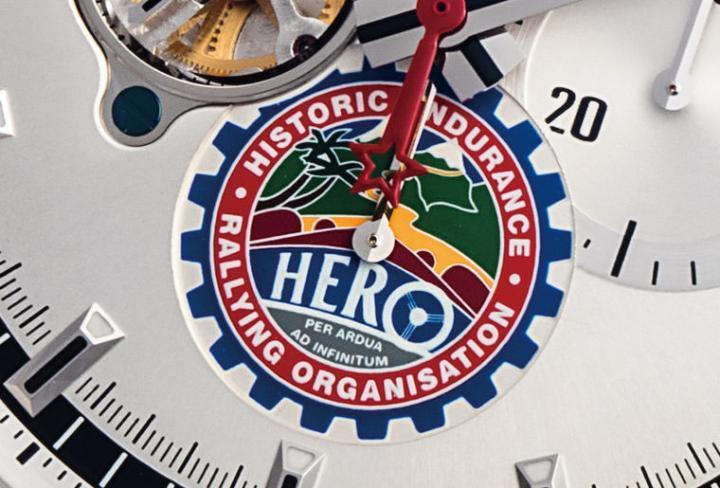 6点钟的HERO Logo是联名款最大的特色，细看组织的Logo其实很有意思，画面的构图是从驾驶座看出去的视点，而字母的O就成了方向盘，更妙的还是右驾，符合组织作为英国单位的身份