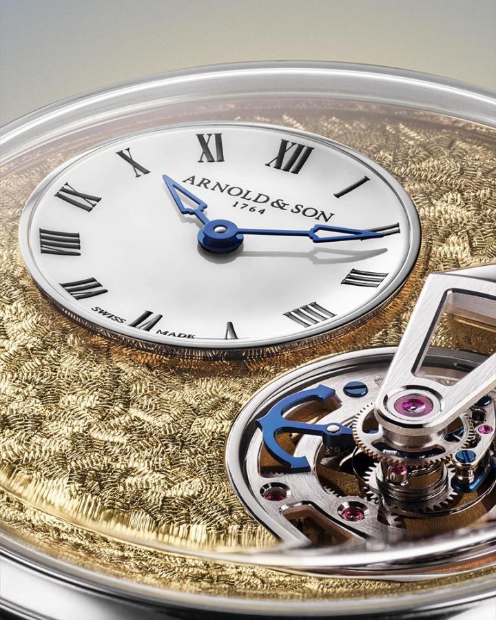 表盘经镂空处理，以嵌入白色蛋白石材质的小时与分钟盘，同时揭露驱动陀飞轮的恒定动力装置。