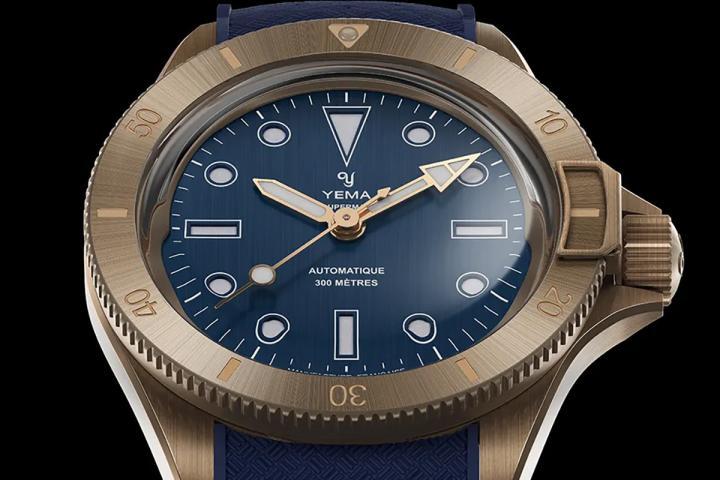 Superman Bronze CMM.10 的核心视觉特色，来自精致的双层蓝白色三明治表盘结构。底层采用 Super‑LumiNova Grade A 夜光涂层，上层表盘经精密镂空设计，使夜光自下方透出，营造层次分明的立体效果。