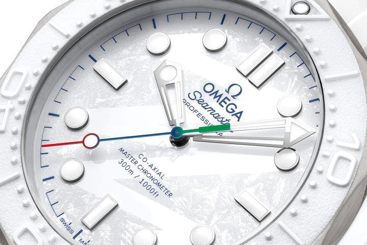 表盘由白色陶瓷制成，表面经雷射雕刻呈现冰霜质感，并加入灵感来自 Milano Cortina 2026 标志中 "26" 数字的指纹纹理图案。中央秒针以红、蓝、绿三色渐层点缀，与本届赛会标志相互呼应。