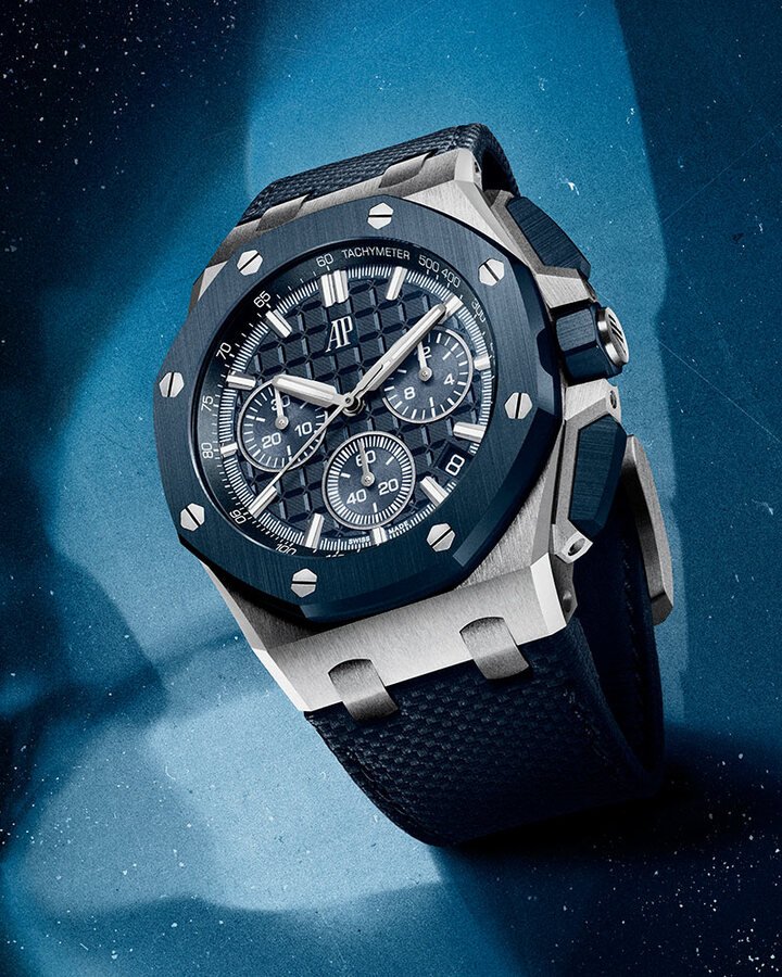 Royal Oak Offshore皇家橡树离岸型系列自动上链计时码表，Mega Tapisserie超大型格纹装饰图案与表盘相得益彰，不仅突显腕表的粗矿外形，也让填充萤光材质的18K白金指针与时标更加耀眼夺目。