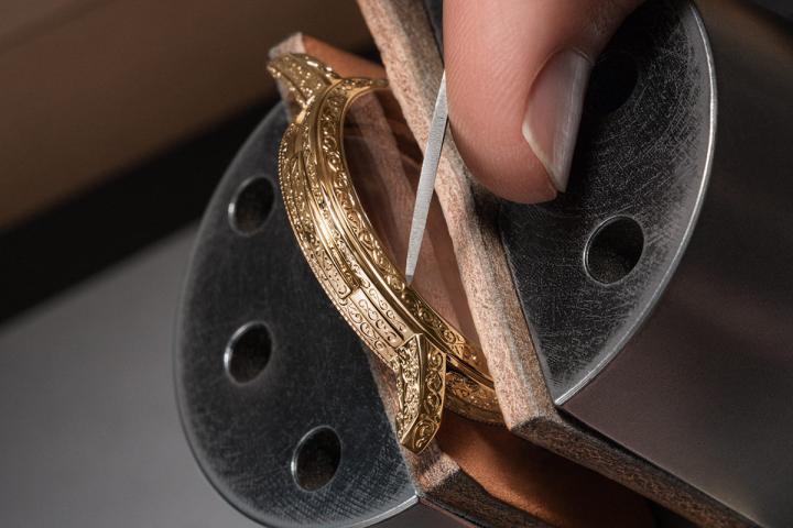 表壳以线雕工艺，悉心镌刻与表盘主题相呼应的精细纹饰。为呈现极富视觉层次的纹饰图案，手工雕刻大师需在金属材质表面精准刻划出数以千计的细密刻纹，每道刻痕深度仅 0.1 至 0.2 毫米。整个工序耗时约 160 小时。