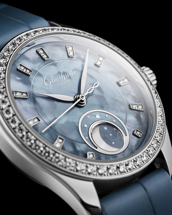 "天际蓝" 珍珠母贝表盘随着光影流转变幻色泽，仿佛摩天大楼的玻璃帷幕映照云影。