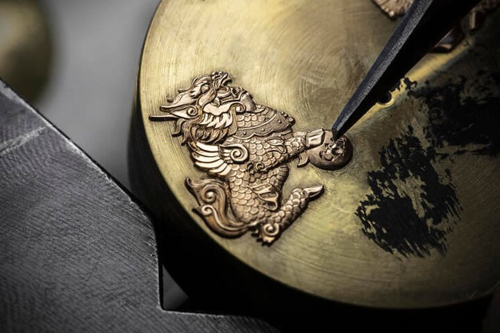 品牌采用浮凸雕刻工艺，再以金丝嵌花技艺将两只麒麟瑞兽固定在面盘上