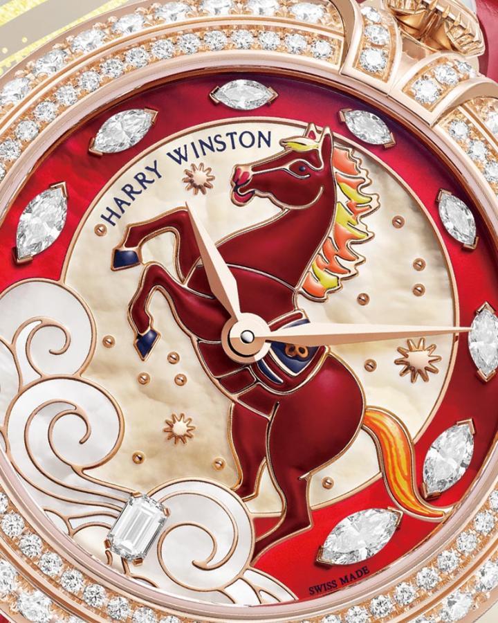 骏马造型透过立体镶贴工艺固定于表盘，马身以手工涂覆红色漆料精心描绘。表盘底部飘逸的祥云以珍珠母贝镶嵌工艺手工制成，此精湛技艺需将极薄珍珠母贝精准裁切后，细腻嵌入边框中。