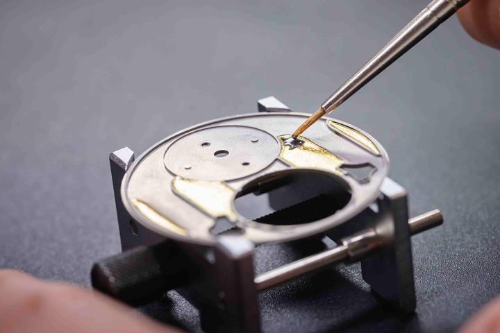 表盘基底采用 18K 白金打造，并涂覆黑色珐琅，再铺上金箔，随后进行高温烧制，珐琅与金箔结合，营造出烛光吊灯倒映在窗户上的视觉效果，赋予表盘引人注目的深邃美感。