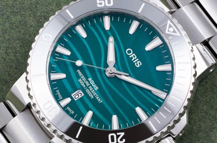 Aquis 长江江豚限量表面盘採蓝绿色珍珠母贝，印制模拟江豚回声定位的波纹，呈现水光粼粼感，兼具美观与象征意义。