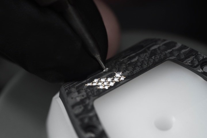 RICHARD MILLE 的宝石镶嵌大师们透过 CNC 数控铣床在 Carbon TPT® 碳纤维上雕琢出极其微小的孔位，精准进行宝石镶嵌的准备工作。