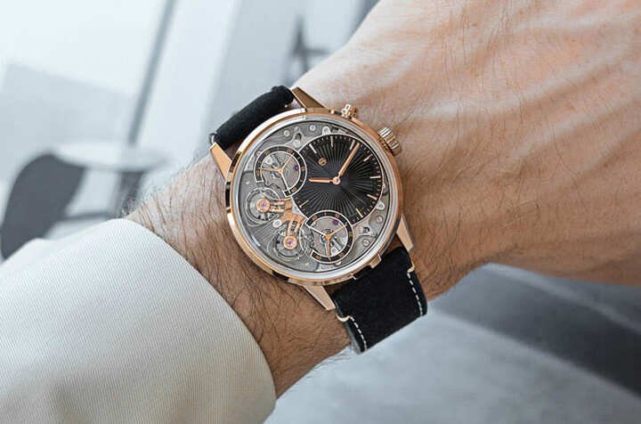 玫瑰金温润奢华，43mm 表径搭配深灰 Alcantara 表带舒适贴合，开面设计让佩戴者可随时欣赏共振机芯与雕花面盘的动态美感。