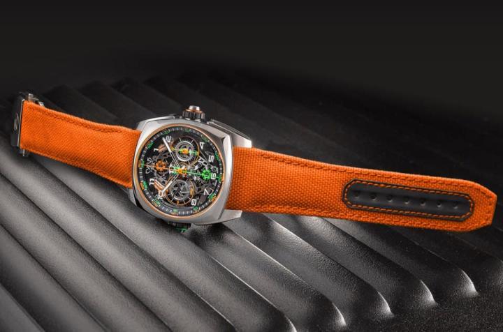手表分别配置橘色织物表带或钛金属炼带。