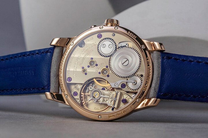 Benu Power Reserve 搭载的 100.2 型手动上链机芯，乃在经典 100.1 型机芯基础上延伸而来，特别整合用于动力储存显示的差速齿轮机构，构成一套额外的机械装置。