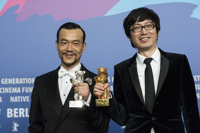 华语电影《白日焰火》导演刁亦男（左）手持「金熊奖」，与影片主演、最佳男演员“银熊奖”得主廖凡合影