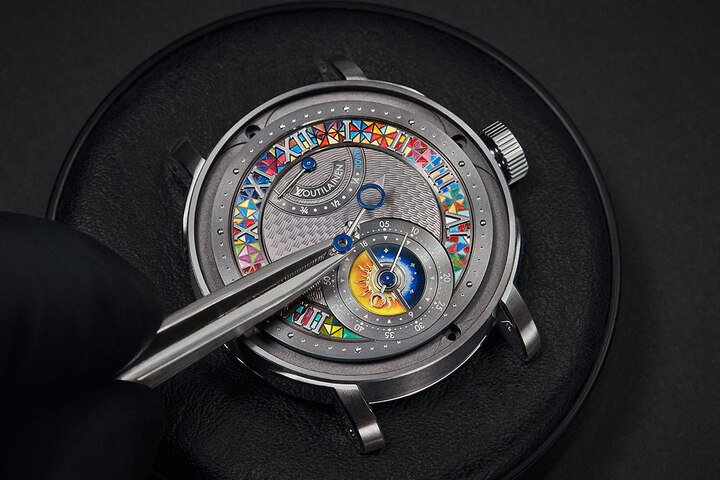 金质表盘的中央展示着手工扭索纹，由布罗贝克扭索纹工坊的工匠在可追溯到18世纪的机器上灵巧而热情地完成——绘制出一种独特而复杂的图案，灵感来自路易威登Damier和Kari Voutilainen的标志性波浪图案。