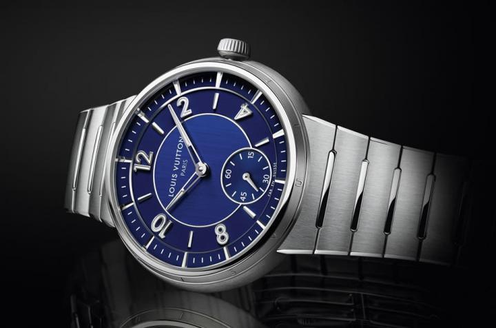 Tambour自动小三针不锈钢腕表有银灰色与深蓝表盘两款，拉丝表盘中心可见LOUIS VUITTON PARIS 字样，展现品牌1854年源于巴黎的出身。