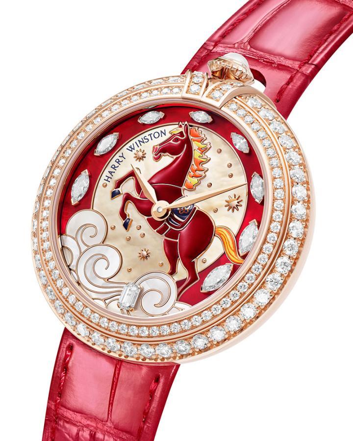 表壳的标志性设计在于 12 点钟位置镶嵌一枚绽放柔光的白色珍珠表冠。珍珠象征智慧、纯洁与丰饶。环绕表盘的两个金色轨道上镶嵌着 118 颗圆形明亮式切工钻石，朝着表冠向上华丽延伸。两道金带结合形成优雅的镶钻拱门，环绕珍珠冠冕。