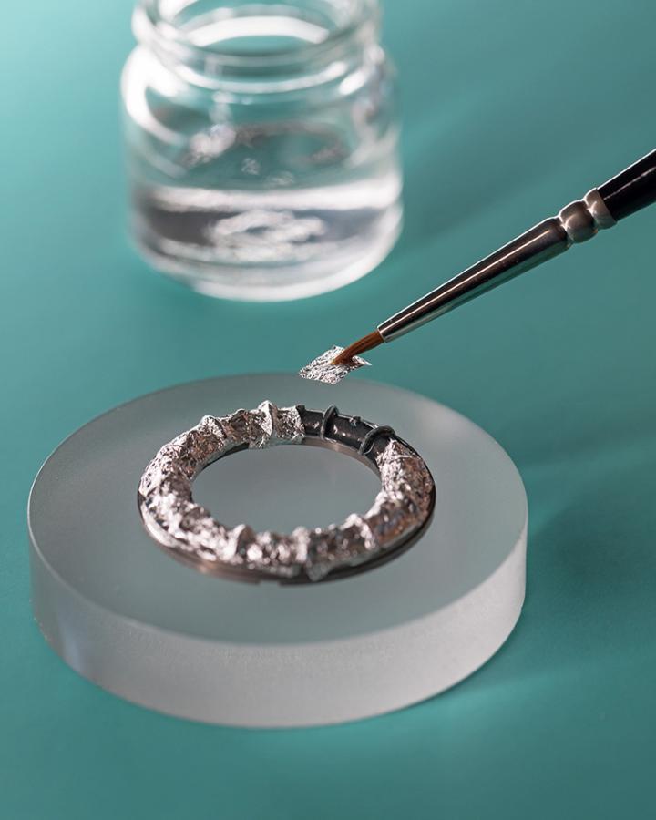 Tiffany 珐琅工艺师自 18K 银箔片中精准裁切出特定形状的细片，铺贴于待装饰的表面上。