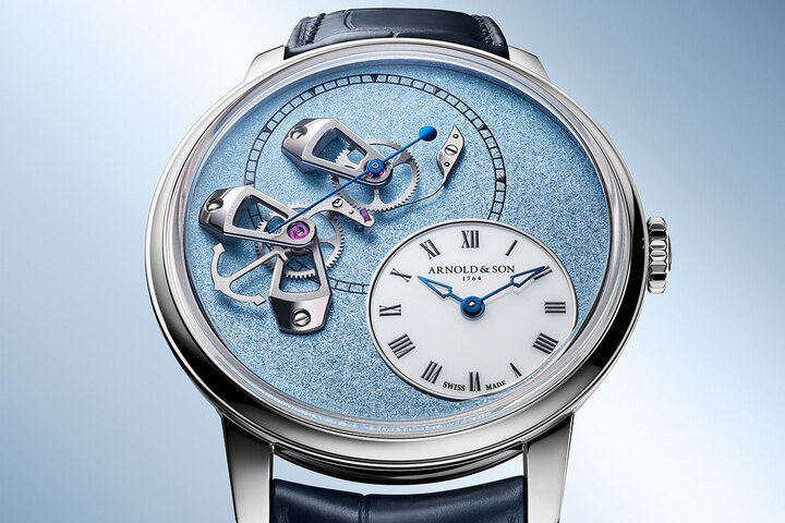Arnold & Son DSTB 将跳秒机制置于表盘正面，计时秒针沿着从 9 点到 12 点的弧线跃动，与 5 点位置的白色蛋白石时分盘彼此呼应。