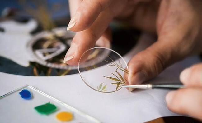 微绘珐琅根据既有的图样微型缩影到面盘上进行彩绘,彩绘师使用极纤细