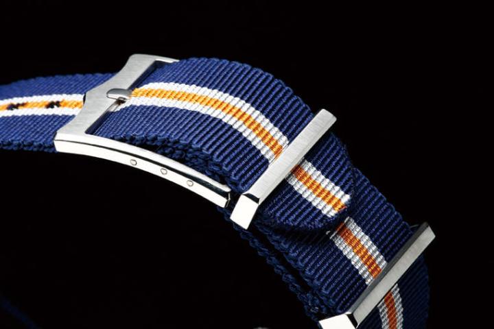 表带所选用的蓝、灰、橙3色，乃是与1973年所推出的Ref.7169/0经典面盘如出一辙，强化了手表整体的视觉和谐度